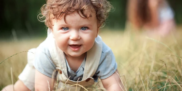 The little baby or year-old child on the grass in sunny summer day. The concept children's months, happy child playing