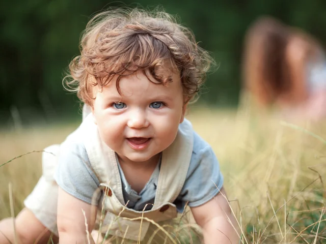 The little baby or year-old child on the grass in sunny summer day. The concept children's months, happy child playing