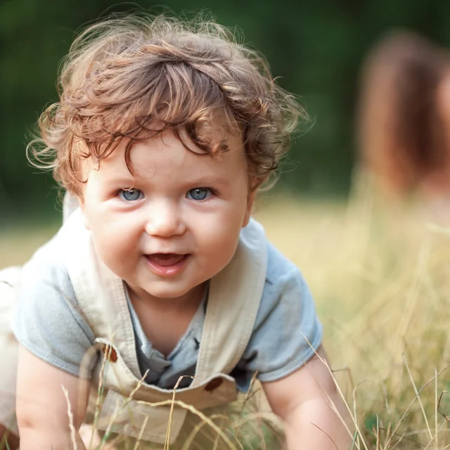 The little baby or year-old child on the grass in sunny summer day. The concept children's months, happy child playing